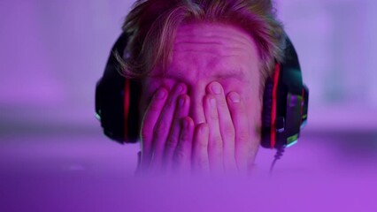 Cyber man losing game in neon lights closeup. Frustrated esport professional