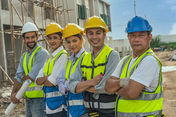 Construction crews and engineers wear safety engineer helmets in uniform with their arms folded around their chests. The team is skilled in construction and confident professionals in construction sit