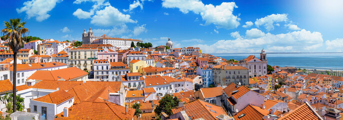 Naklejka na ściany i meble Panoramic view of the beautiful skyline of Lisbon, Portugal, with red roofed, colorful houses in the Alfama district during a sunny day