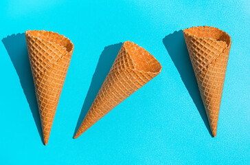 Three waffle ice cream cups on a blue background in hard light. Top view, horizontal.