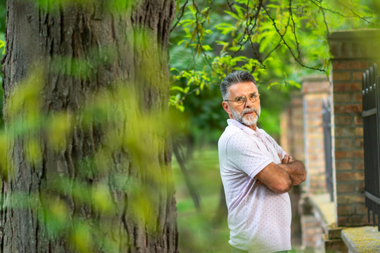 Portrait of Mature man Caucasian smiling and looking at camera, outside in park. Close-up of a man smiling. Image of a smiling man in the park.