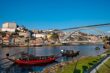 Fototapeta na wymiar Oporto traditional boats, anchored on the Douro River, view from Vila Nova de Gaia City side with the cityscape of Porto city as Background.