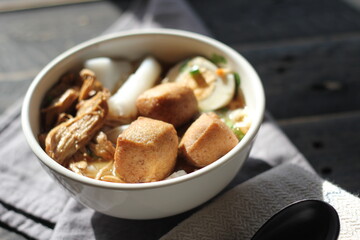 Thai food, Chinese roll noodle soup served in a white cup on a black wooden table.