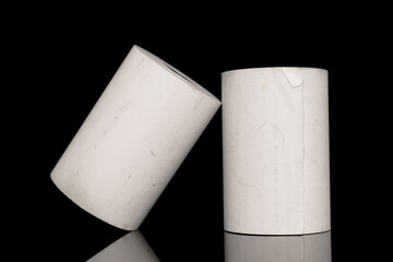 Two rolls of paper cash register tape, close-up isolated on black.