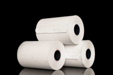 Three rolls of paper cash register tape, close-up isolated on black.