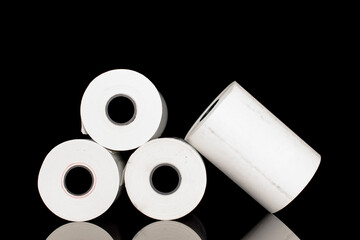 Four rolls of paper cash register tape, close-up isolated on black.