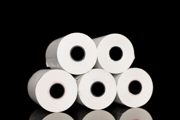 Several rolls of paper cash register tape, close-up isolated on black.