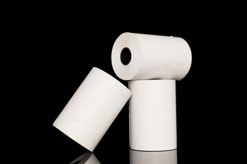 Three rolls of paper cash register tape, close-up isolated on black.