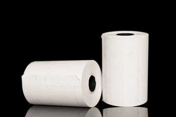 Two rolls of paper cash register tape, close-up isolated on black.