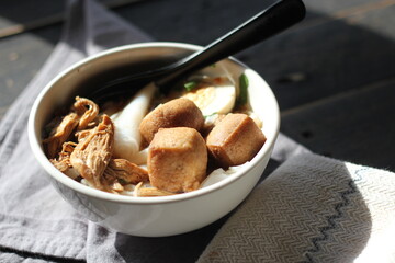 Thai food, Chinese roll noodle soup served in a white cup on a black wooden table.