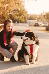 Preteen girl patting dog zenenhund. Little girl walking with dog in city, posing with pet.