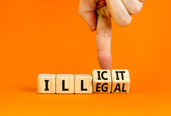 Illegal or illicit symbol. Businessman turns wooden cubes and changes the concept word Illegal to Illicit. Beautiful orange table and background. Business and illegal or illicit concept. Copy space.