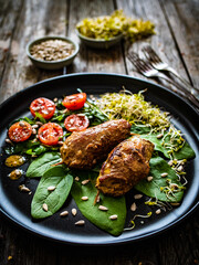 Wrapped pork with greens on wooden table
