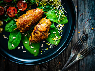 Wrapped pork with greens on wooden table
