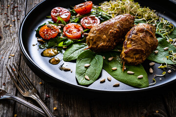 Wrapped pork with greens on wooden table
