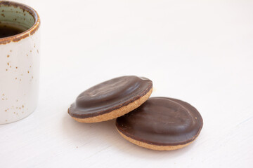 Two chocolate cookies and Coffee, tea in white ceramic mug on white background