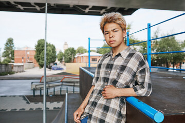 Fototapeta premium Waist up portrait of teenage boy looking at camera in skatepark outdoors in urban area, copy space