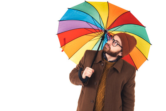 Weather concept. Is it still raining. Caucasian guy looking out of his rainbow umbrella over white background. High quality photo