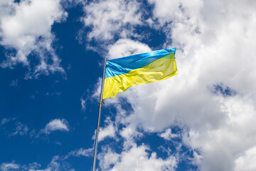Ukrainian Flag, blue and yellow colors, sky with clouds. National symbol of Ukkraine.
