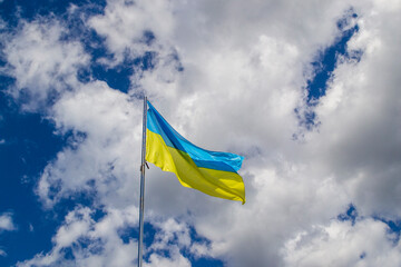 Ukrainian Flag, blue and yellow colors, sky with clouds. National symbol of Ukkraine.