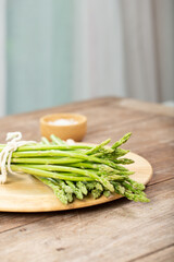 Asparagus is green and straight vegetable. Fresh, green asparagus is crispy for cook on wood table with salt