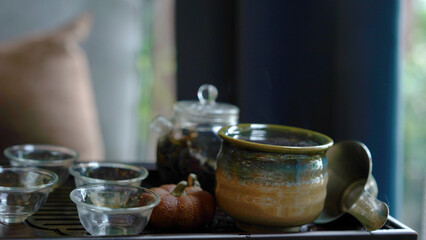 Traditional tea set tray with modern transparent pot and clear small cup in cozy Chinese room. Natural healthy hot clear drink with dried leaves give good aroma and relax for drink.