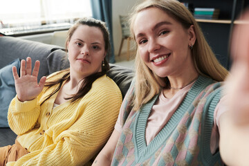 Young Caucasian woman and her sister with Down syndrome spending time togetehr at home having fun...
