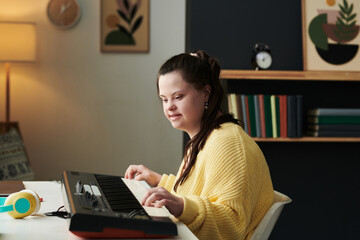 Portrait of modern young Caucasian girl with Down syndrome spending spare time at home playing...