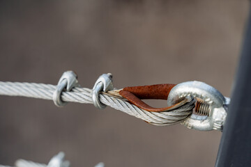 Metal fastening of the braided rope, screed of the cable on the bolts, the ring holds the tension of the iron cable.