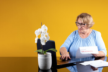 An elderly woman enters data from paper electricity bills into a laptop. The concept of...