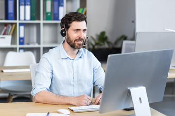 Portrait of a man with a headset for a video call, a man working in the office at the computer and smiling