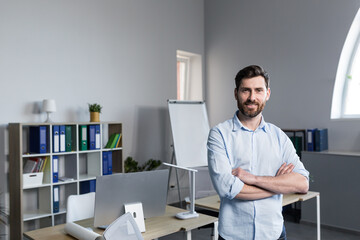 Fototapeta premium Portrait of successful businessman, man smiling and working on laptop in modern bright office
