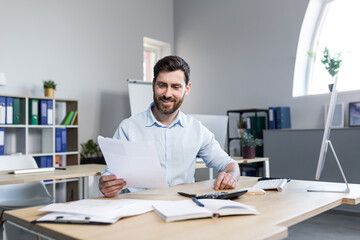 Happy businessman at paper work, examining financial documents, man at work working in the office