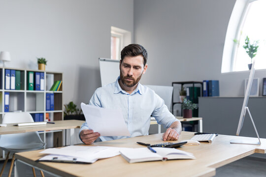 Thinking businessman working with documents in the office, man reviewing financial reports