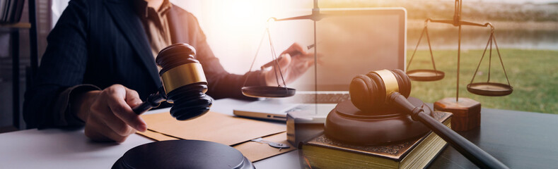 Justice and law concept.Male judge in a courtroom with the gavel, working with, computer and docking keyboard, eyeglasses, on table in morning light