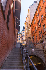 Stairs at the road Tunnelgatan with 1800s apartment houses with tin roofs, chimneys, dorms and towers down town a sunny day in Stockholm