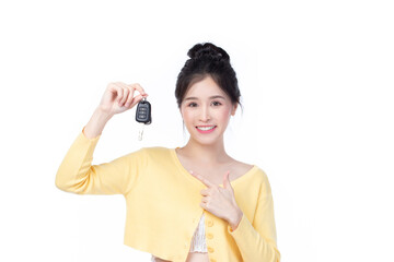 Beautiful young Asian woman wearing yellow shirt feeling happy and smile holding the keys of the car on white background.