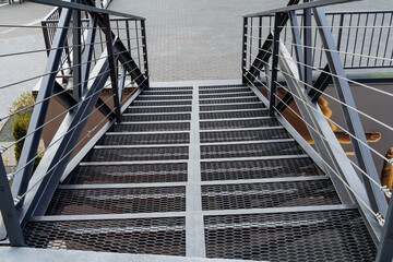Iron staircase transition between floors. pedestrian ladder above the road, railings made of profile, metal cables stretched between the beams.