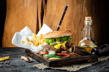 Homemade burger with juicy meat cutlet, vegetables, sauce French fries on rustic wooden background. fast food and junk food concept