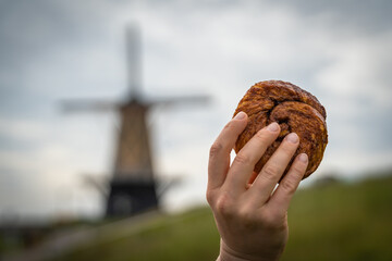 Traditional dutch pastry called Zeeuwse Bolus on blurred background with a windmill