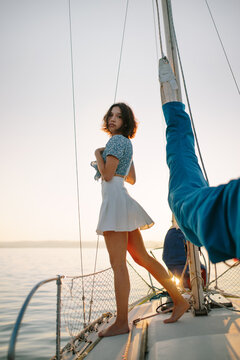 Calm young lady admiring nature while standing on sailboat