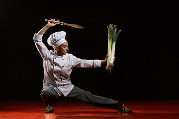 Young female mime artist with knife and leeks performing martial arts pose