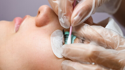 The master removes the composition for lamination from the client's eyelashes with a cotton swab....