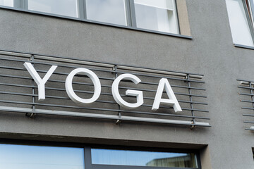 Fototapeta na wymiar A building with a sign for yoga classes, yoga text hanging on the wall, a sign of a club of oriental practices, advertising on the street, white letters in the name of yoga.