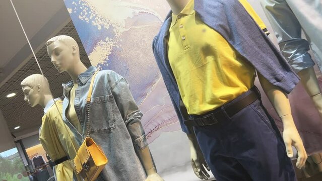 Mannequins stand in the window of a clothing store or boutique. Dutch angle