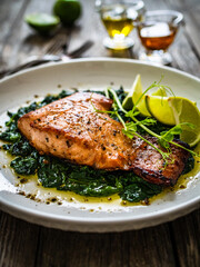 Fried salmon steak with spinach and lime served on wooden table
