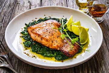 Fried salmon steak with spinach and lime served on wooden table
