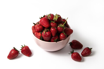 Fresh strawberries in a pink bowl on a white background