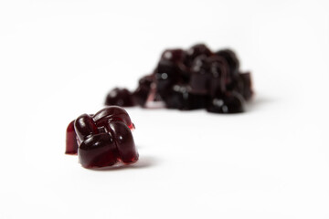 Dark red cherry homemade gelatin candy on white background with a heap in the background unfocused