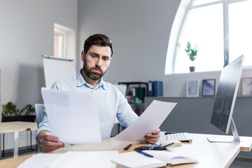 Young male businessman. Accountant, economist, financier. Works with documents, papers, reports,...